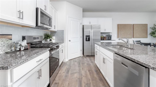 kitchen with stone counters, appliances with stainless steel finishes, sink, and white cabinets