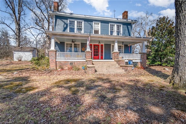 view of front of house featuring a ceiling fan, a shed, covered porch, a chimney, and an outdoor structure