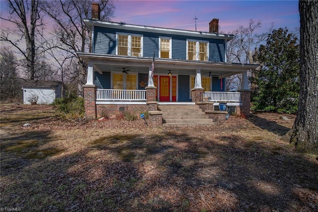 view of front facade with ceiling fan, an outbuilding, covered porch, and a chimney