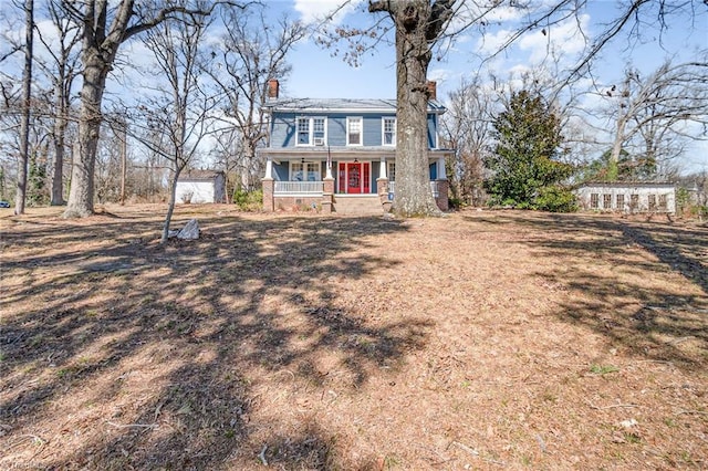 view of front of property with a porch, an outdoor structure, and a chimney