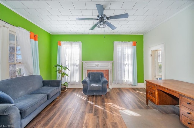 living area featuring a fireplace, wood finished floors, a ceiling fan, and crown molding