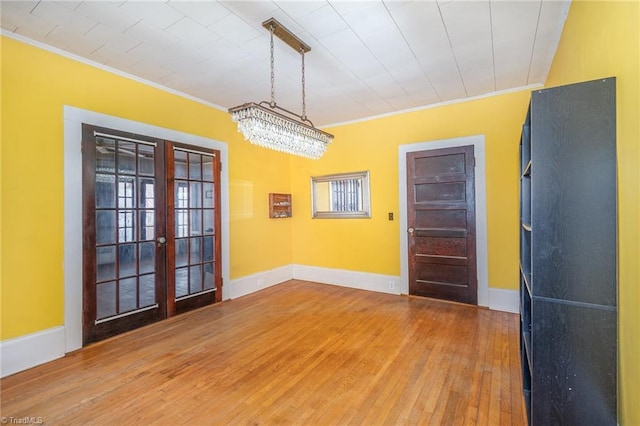 unfurnished room featuring wood finished floors, french doors, baseboards, and ornamental molding