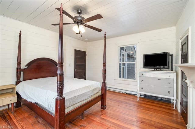 bedroom featuring wooden walls, ceiling fan, and hardwood / wood-style floors