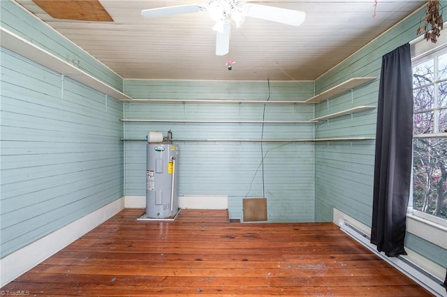 interior space with wood finished floors, electric water heater, baseboard heating, and ceiling fan