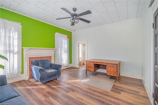 sitting room with a ceiling fan, baseboards, and wood finished floors