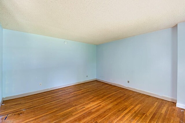 1281 Woodbrook Dr, Kernersville, NC 27284 - spare room featuring wood-type flooring, a textured ceiling, and baseboards
