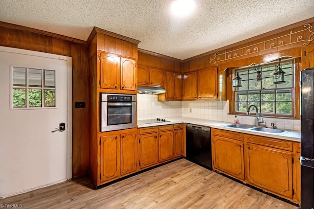 1281 Woodbrook Dr, Kernersville, NC 27284 - kitchen featuring black appliances, a sink, a textured ceiling, brown cabinets, and under cabinet range hood
