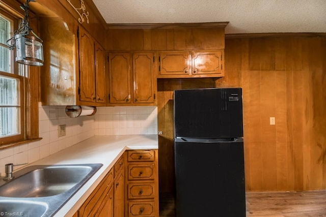 1281 Woodbrook Dr, Kernersville, NC 27284 - kitchen featuring freestanding refrigerator, a textured ceiling, backsplash, brown cabinetry, and a sink
