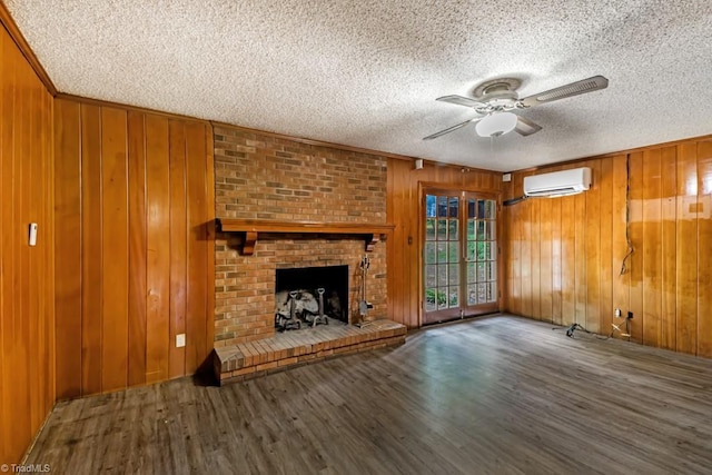 1281 Woodbrook Dr, Kernersville, NC 27284 - unfurnished living room featuring a wall mounted air conditioner, a textured ceiling, a ceiling fan, wood walls, and wood finished floors