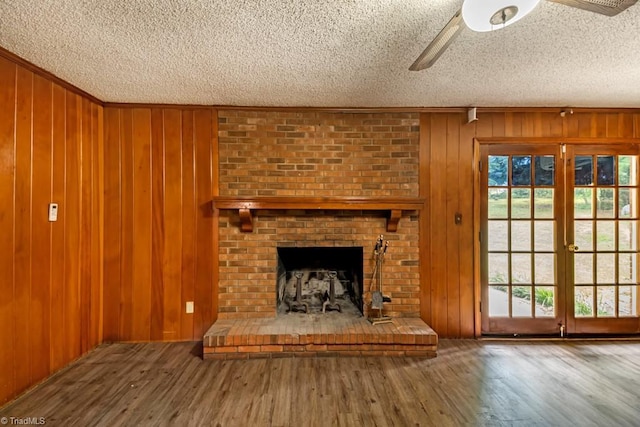 1281 Woodbrook Dr, Kernersville, NC 27284 - unfurnished living room featuring healthy amount of natural light, ceiling fan, a textured ceiling, wood finished floors, and wooden walls