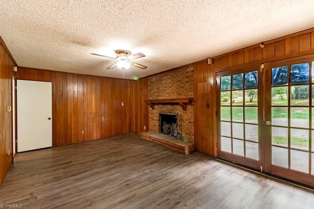 1281 Woodbrook Dr, Kernersville, NC 27284 - unfurnished living room with ceiling fan, a textured ceiling, wood walls, wood finished floors, and a brick fireplace