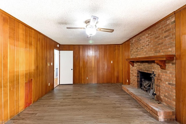 1281 Woodbrook Dr, Kernersville, NC 27284 - unfurnished living room featuring a textured ceiling, a ceiling fan, a brick fireplace, wood finished floors, and crown molding