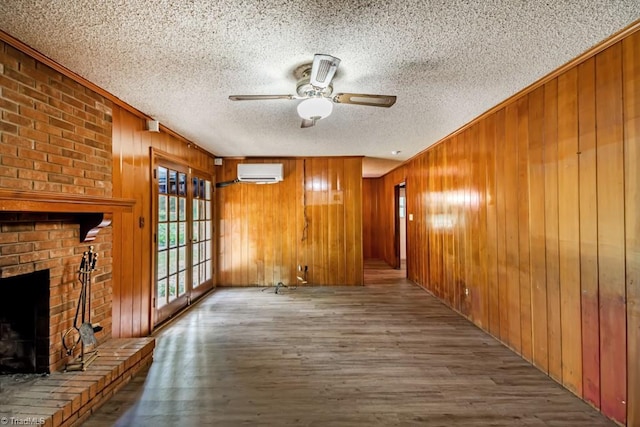 1281 Woodbrook Dr, Kernersville, NC 27284 - unfurnished living room featuring a wall mounted AC, a textured ceiling, wooden walls, wood finished floors, and ornamental molding