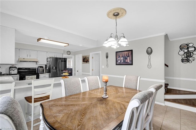 tiled dining room featuring a chandelier and ornamental molding