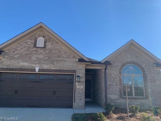 view of front of home featuring a garage, concrete driveway, and brick siding