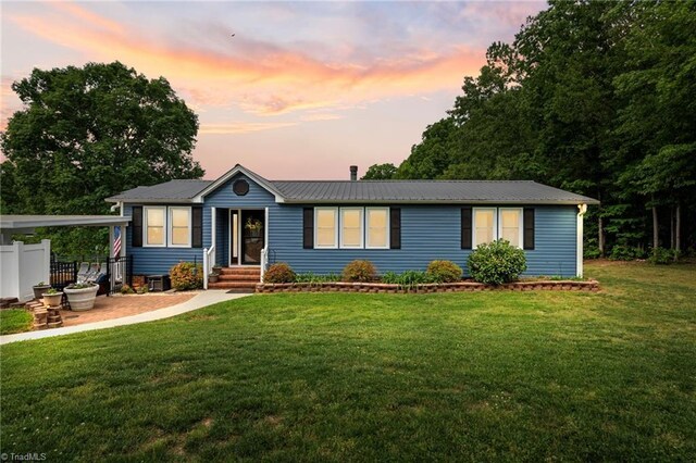 view of front of property with a lawn, fence, and metal roof