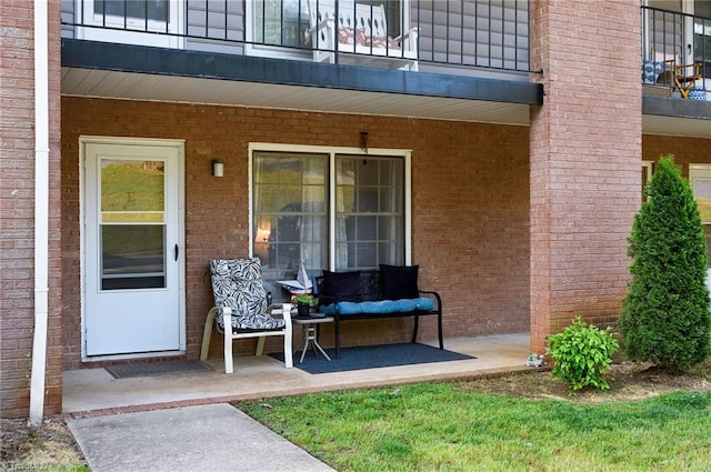 entrance to property with brick siding and a balcony