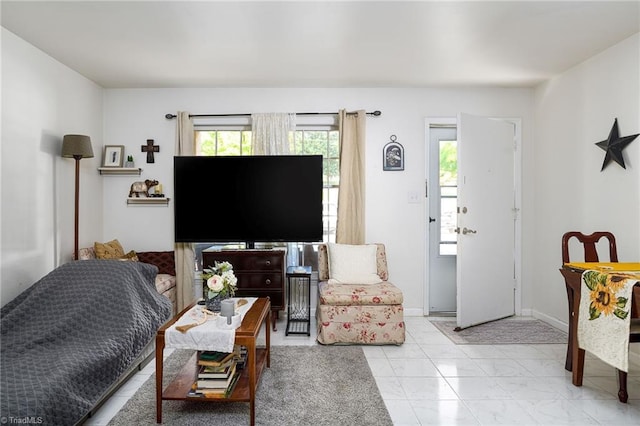 living room featuring baseboards, plenty of natural light, and marble finish floor