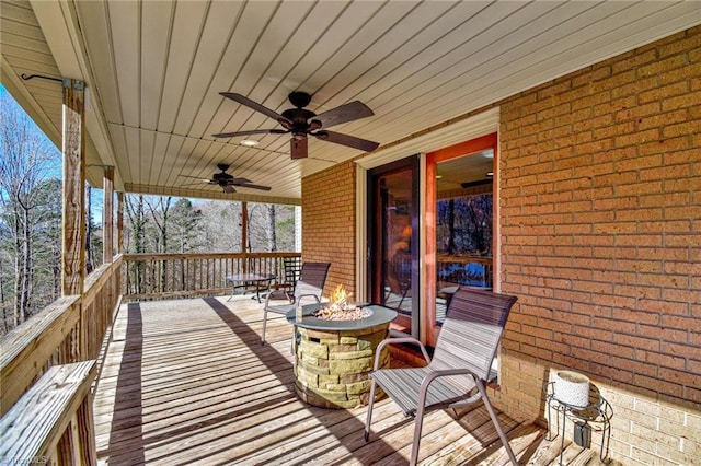 wooden deck with ceiling fan and an outdoor fire pit