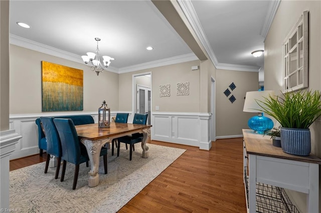 dining room with ornamental molding, hardwood / wood-style floors, and an inviting chandelier