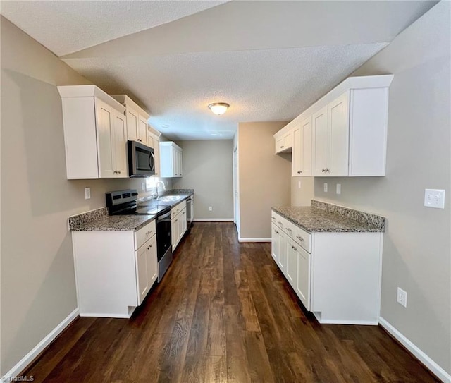 kitchen featuring appliances with stainless steel finishes, dark wood-type flooring, baseboards, and a textured ceiling