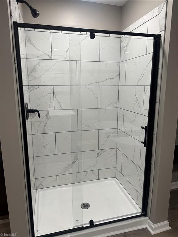 bathroom featuring a shower with door and wood-type flooring