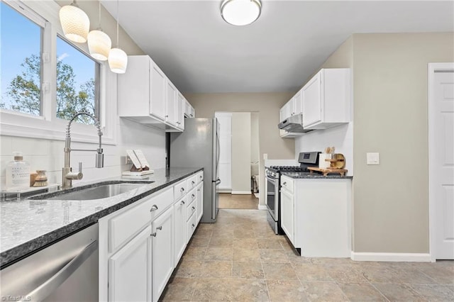 kitchen with stainless steel appliances, sink, dark stone countertops, decorative light fixtures, and white cabinets