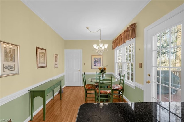 dining space featuring a chandelier, ornamental molding, baseboards, and wood finished floors