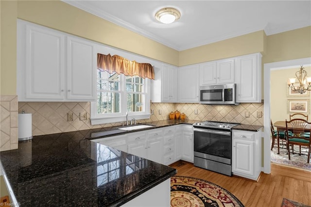 kitchen featuring appliances with stainless steel finishes, white cabinets, a sink, and a chandelier