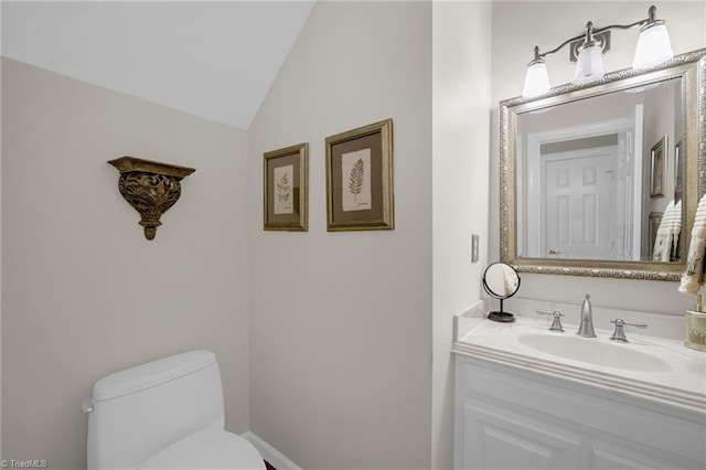 half bath with toilet, vaulted ceiling, and vanity