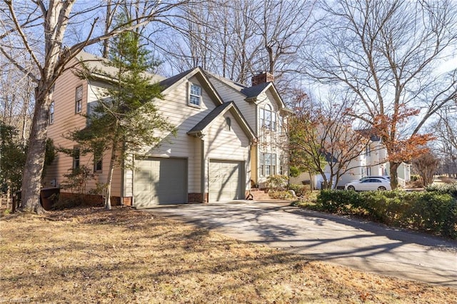 view of side of property featuring a garage, a chimney, and concrete driveway