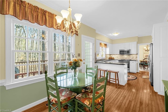 dining area featuring a chandelier, baseboards, hardwood / wood-style flooring, and crown molding