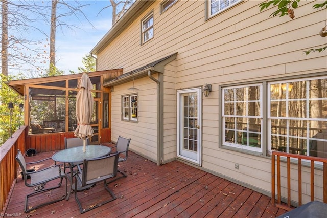 wooden terrace featuring a sunroom and outdoor dining space