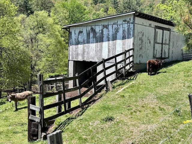 view of pole building with a lawn, fence, and a forest view