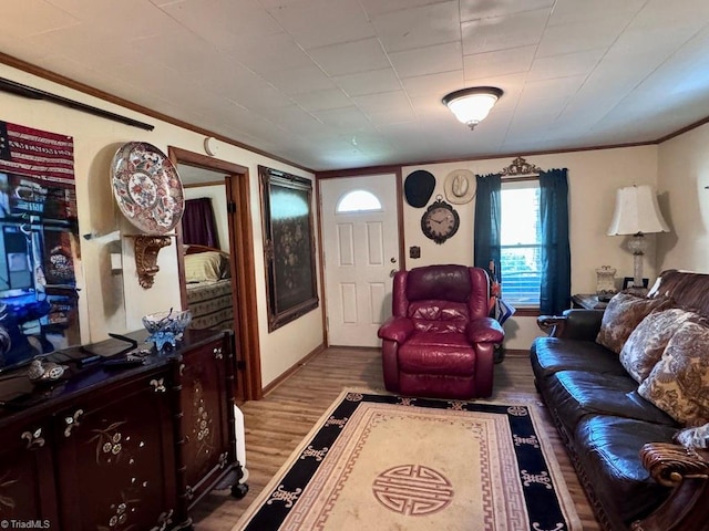 living area with crown molding, baseboards, and wood finished floors