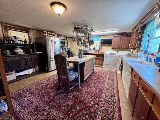 kitchen with brown cabinetry, open shelves, separate washer and dryer, a sink, and stainless steel appliances