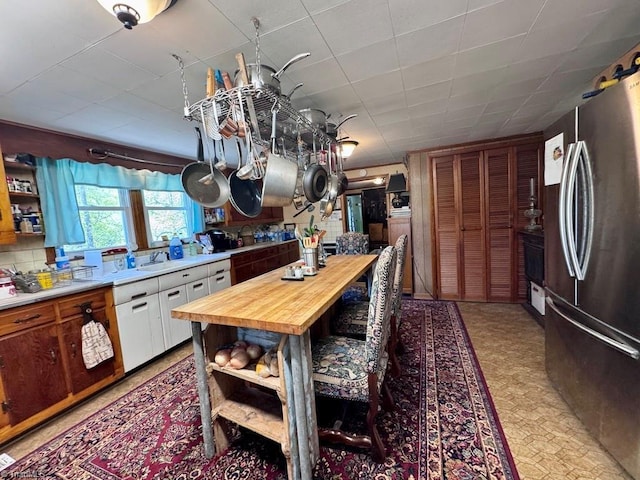 kitchen with a sink, freestanding refrigerator, open shelves, and butcher block counters