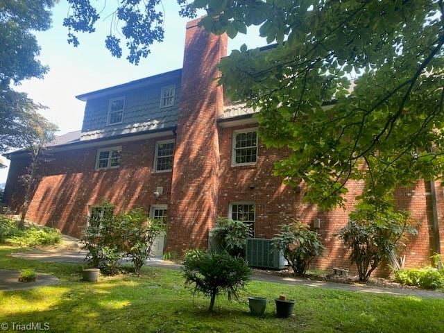 back of house featuring central AC unit and a lawn