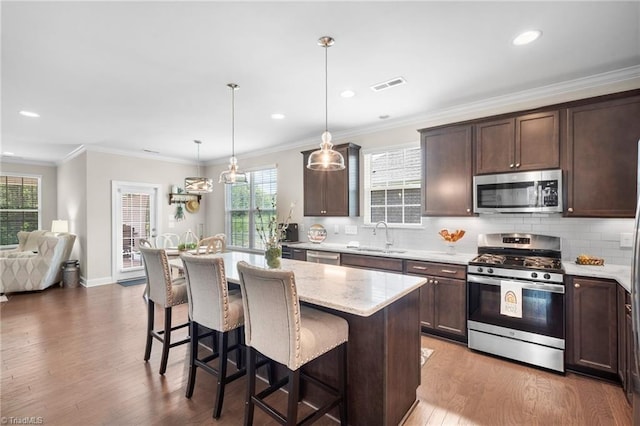 1417 Blooming Mountain Way, Kernersville, NC 27284 - kitchen featuring a kitchen breakfast bar, visible vents, dark brown cabinets, a sink, and stainless steel appliances