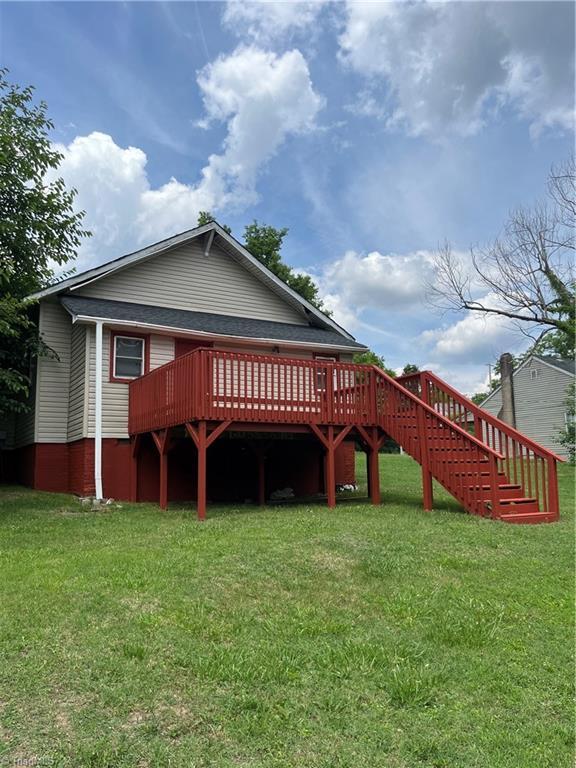 rear view of house featuring a wooden deck and a yard