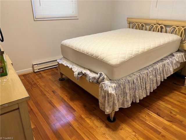 bedroom featuring dark wood-type flooring and a baseboard heating unit