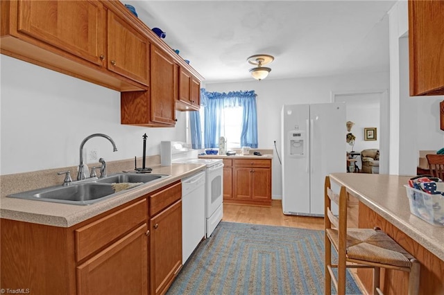 kitchen with light wood-type flooring, white appliances, and sink