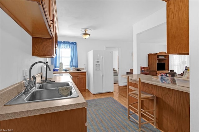 kitchen featuring light hardwood / wood-style floors, white fridge with ice dispenser, and sink