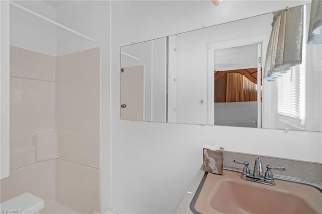 bathroom with toilet, sink, and walk in shower