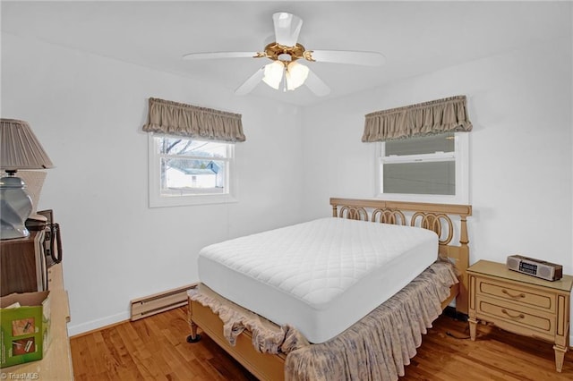 bedroom with baseboard heating, ceiling fan, and wood-type flooring