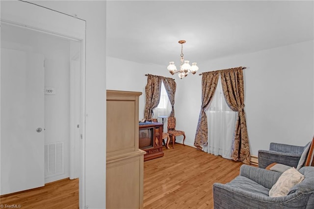 sitting room with light wood-type flooring and an inviting chandelier