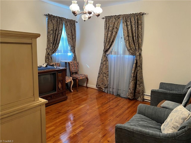 living area with hardwood / wood-style flooring, a notable chandelier, and a baseboard heating unit