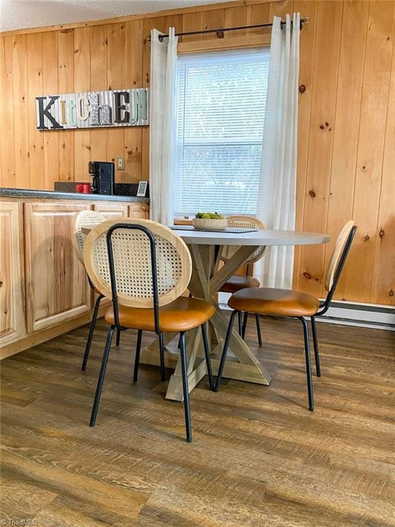 dining area featuring a baseboard radiator, wooden walls, and dark wood-type flooring