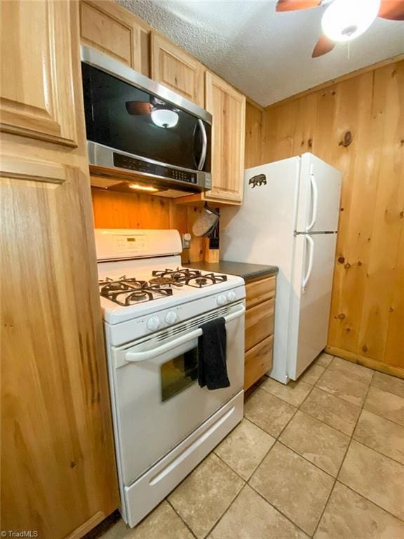 kitchen featuring light tile patterned flooring, wooden walls, light brown cabinets, white appliances, and ceiling fan