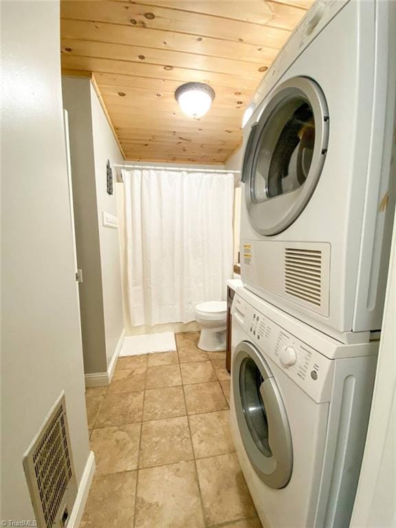 laundry room with light tile patterned floors, stacked washing maching and dryer, wood ceiling, visible vents, and laundry area